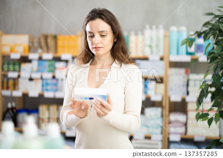 Adult woman chooses ointment at pharmacy Adult woman chooses ointment at pharmacy 137357285