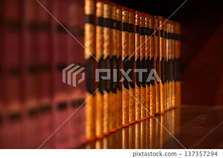 Ornate gold-bound books lining a library shelf, symbolizing knowledge and education 137357294