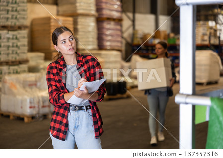Girl warehouse worker checking inventory Girl warehouse worker checking inventory 137357316