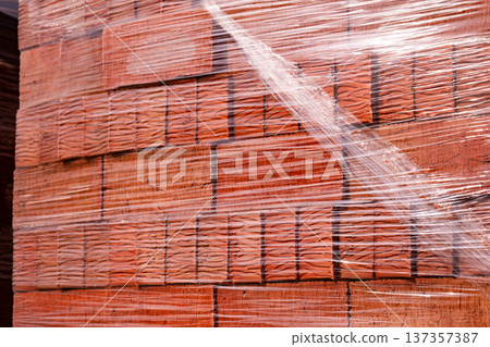 Building materials: new red bricks stacked on a pallet, wrapped in clear plastic Building materials: new red bricks stacked on a pallet, wrapped in clear plastic 137357387