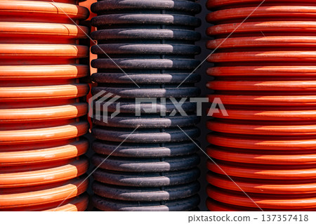 Corrugated orange and black pipes forming a ribbed industrial texture background 137357418