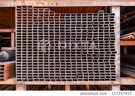 Stacked rectangular metallic profiles in a warehouse for construction and industry Stacked rectangular metallic profiles in a warehouse for construction and industry 137357457
