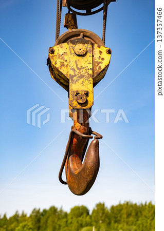 Heavy industrial crane hook lifting equipment against a clear blue sky 137357466