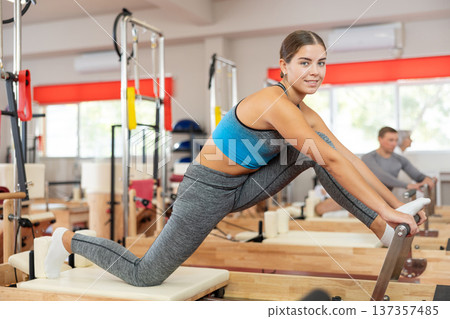 Young woman doing stretching on pilates machine 137357485