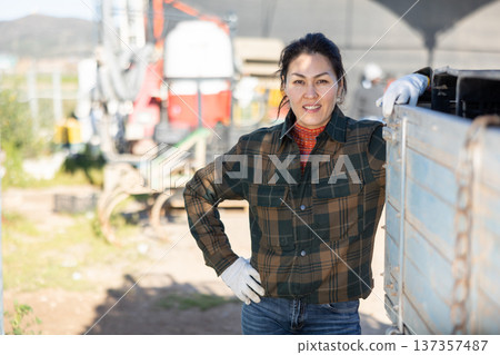 Portrait of positive female tractor driver in farm backyard 137357487