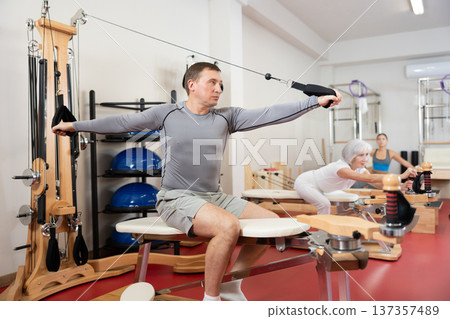 Adult man training her arms using straps Adult man training her arms using straps 137357489