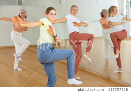 Teen girl with family doing aerobics exercises with group of people in dance center Teen girl with family doing aerobics exercises with group of people in dance center 137357526