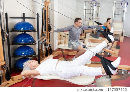 Elderly woman training her legs using straps Elderly woman training her legs using straps 137357533