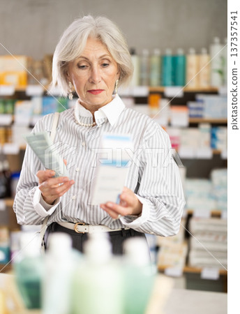 Elderly woman chooses cream at pharmacy Elderly woman chooses cream at pharmacy 137357541