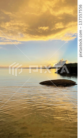 A calm sea and fantastical golden clouds at sunrise in Nakijin Village, Okinawa Prefecture A calm sea and fantastical golden clouds at sunrise in Nakijin Village, Okinawa Prefecture 137357556