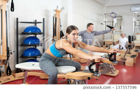 Young girl during Pilates training performs exercises and tasks on heron pulley tower Young girl during Pilates training performs exercises and tasks on heron pulley tower 137357596