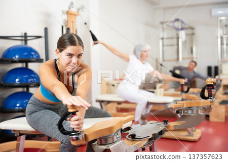 Young woman stretching her arms using pilates machine Young woman stretching her arms using pilates machine 137357623