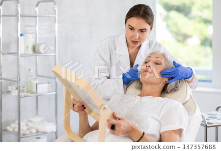 Mature patient with mirror, doctor with gloves 137357688