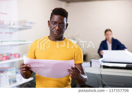 Employee of printing house checks the quality of printing in computer room Employee of printing house checks the quality of printing in computer room 137357706