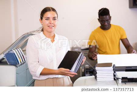 Smiling young female typographer showing new notepads in the middle of the typography 137357713