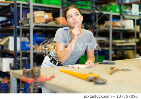 Portrait of thoughtful young woman worker checking order list Portrait of thoughtful young woman worker checking order list 137357850
