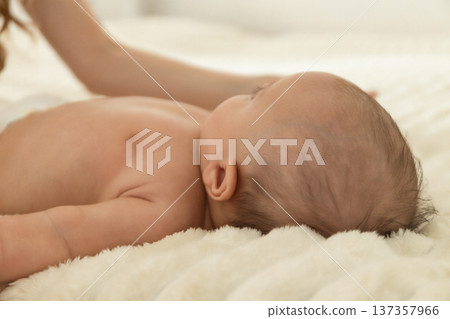 A mother gently interacts with her newborn on a soft blanket 137357966