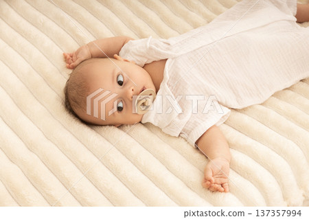 A baby relaxes on a plush blanket, curiously looking around A baby relaxes on a plush blanket, curiously looking around 137357994