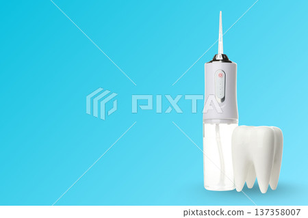 Dental cleaning device beside tooth model on blue Dental cleaning device beside tooth model on blue 137358007