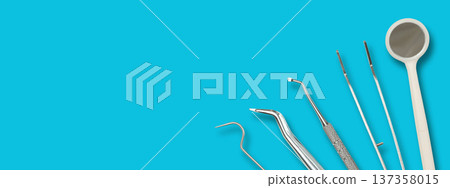 Dental instruments arranged on a solid blue backdrop 137358015
