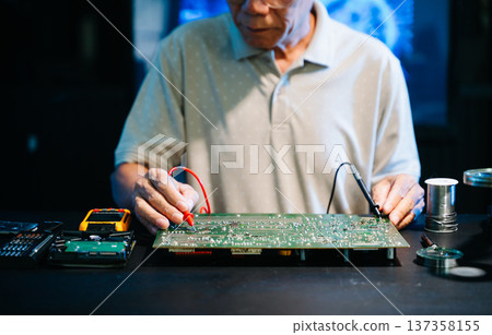 Closeup of expert soldering a green PCB board using precision tools. Ideal for electronics, circuit repair, engineering, tech 137358155