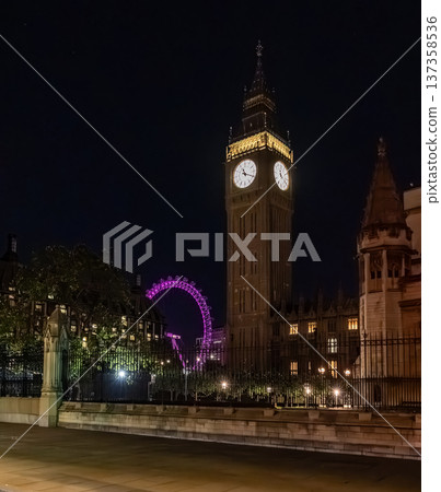 Big Ben clock tower seen from behind iron fencing at night. The layered view adds depth to London city landmark imagery. Big Ben clock tower seen from behind iron fencing at night. The layered view adds depth to London city landmark imagery. 137358536