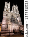 Westminster Abbey, London. The Gothic architecture is beautifully illuminated under the evening sky, showcasing the detailed facade and majestic towers. 137358538