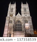 Westminster Abbey, London. The Gothic architecture is beautifully illuminated under the evening sky, showcasing the detailed facade and majestic towers. 137358539