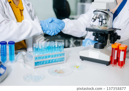 scientists in lab coats conducting research, handling glassware, and working with chemicals scientists in lab coats conducting research, handling glassware, and working with chemicals 137358877