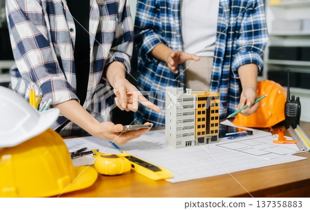Two colleagues discussing data working and tablet, laptop with architectural project at construction site Two colleagues discussing data working and tablet, laptop with architectural project at construction site 137358883