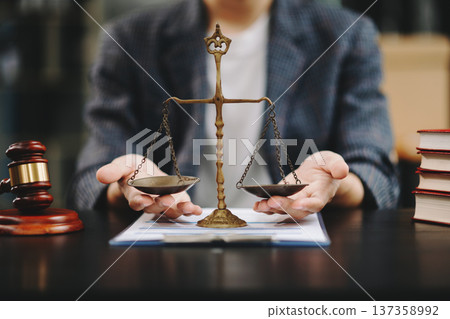 Male lawyer in the office with brass scale on wooden table. justice and law concept in morning light 137358992