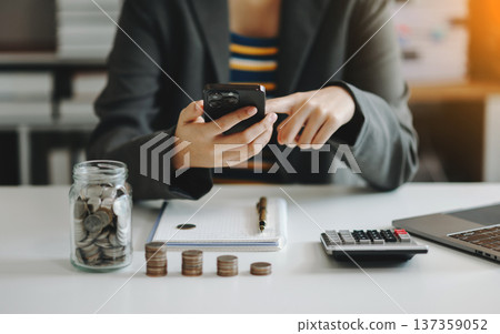 businesswoman holding coins putting in glass with using smartphone and calculator to calculate concept saving money for finance accounting in office businesswoman holding coins putting in glass with using smartphone and calculator to calculate concept saving money for finance accounting in office 137359052