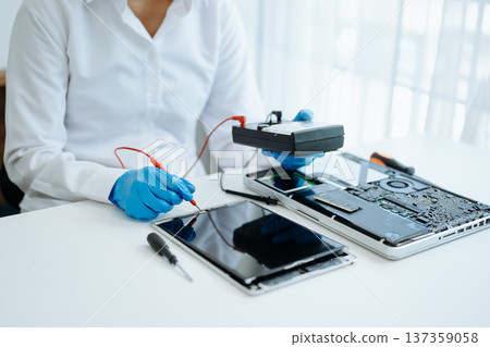 Electronics technician, electronic engineering electronic repair,electronics measuring and testing, repair and maintenance concepts.uses a voltage meter to check and upgrade 137359058