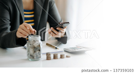 businesswoman holding coins putting in glass with using smartphone and calculator to calculate concept saving money for finance accounting in office businesswoman holding coins putting in glass with using smartphone and calculator to calculate concept saving money for finance accounting in office 137359103