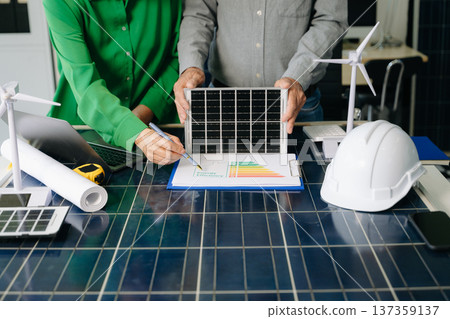 Two engineers collaborate on solar and wind energy, driving clean innovation and sustainability. A vision of teamwork 137359137