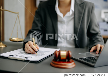 justice and law concept. Male judge in a courtroom the gavel, working with smart phone and laptop and digital tablet computer on desk 137359351