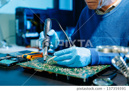 Close up of technician soldering and repairing circuit board in a modern laboratory, electronics repair, engineering, technology, maintenance and quality control concept. Close up of technician soldering and repairing circuit board in a modern laboratory, electronics repair, engineering, technology, maintenance and quality control concept. 137359391