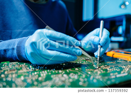 Close up of technician soldering and repairing circuit board in a modern laboratory, electronics repair, engineering, technology, maintenance and quality control concept. 137359392