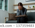 Coping with Emotions. Woman in distress holding her head while sitting on a couch. 137359483
