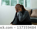 Struggling with Stress. Woman sitting on a couch, holding her head in frustration. 137359484