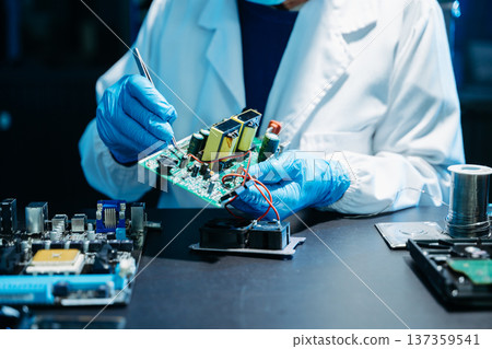 Closeup of expert soldering a green PCB board using precision tools. Ideal for electronics, circuit repair, engineering, tech Closeup of expert soldering a green PCB board using precision tools. Ideal for electronics, circuit repair, engineering, tech 137359541