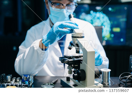 IT technician using microscope to inspect a motherboard in a modern lab. Electronics repair, precision work, troubleshooting, and system diagnostics 137359607