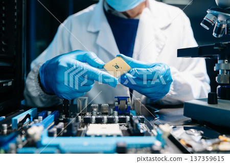 The technician is putting the CPU on the socket of the computer motherboard. electronic engineering electronic repair, electronics measuring The technician is putting the CPU on the socket of the computer motherboard. electronic engineering electronic repair, electronics measuring 137359615
