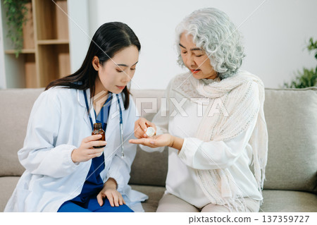 Female doctor helping senior woman take medication at home. Healthcare, elderly care, medical consultation, home healthcare, treatment guidance and wellness concept. Female doctor helping senior woman take medication at home. Healthcare, elderly care, medical consultation, home healthcare, treatment guidance and wellness concept. 137359727