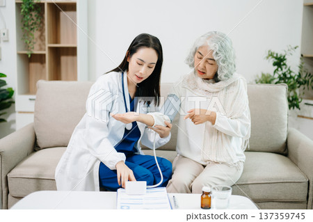 Doctor assisting elderly woman with blood pressure monitoring at home, highlighting healthcare, hypertension prevention, medical consultation 137359745