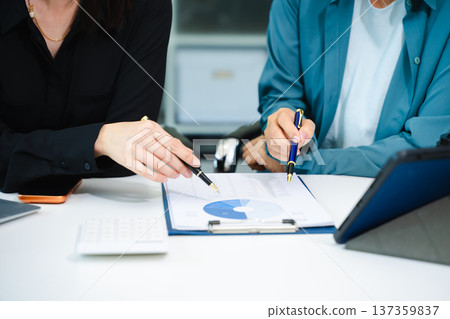 Asian businesswomen celebrating success in modern office. Teamwork, leadership, mentoring and collaboration concept with laptop and tablet. 137359837
