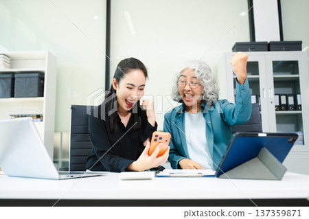 Senior and junior Asian businesswomen discussing documents in modern office, mentorship, teamwork, leadership Senior and junior Asian businesswomen discussing documents in modern office, mentorship, teamwork, leadership 137359871