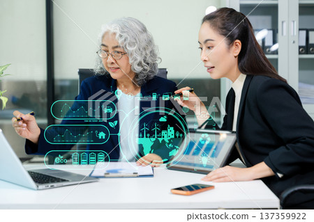 Asian business women analyzing clean energy and renewable energy data using digital dashboard, reflecting ESG strategy, sustainability, innovation, and modern corporate environment. 137359922