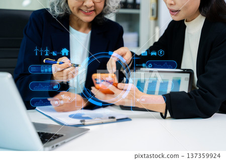 Asian business women analyzing clean energy and renewable energy data using digital dashboard, reflecting ESG strategy, sustainability, innovation, and modern corporate environment. Asian business women analyzing clean energy and renewable energy data using digital dashboard, reflecting ESG strategy, sustainability, innovation, and modern corporate environment. 137359924