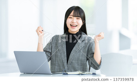 一位年輕女子/女商人對著電腦揮拳慶祝。 一位年輕女子/女商人對著電腦揮拳慶祝。 137359978